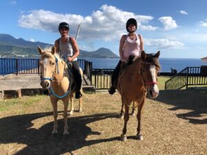 Two guests on horses next to Dominica beach