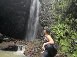 Woman kneeling next to a roaring waterfall