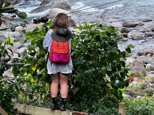 Woman standing on ledge overlooking a stream